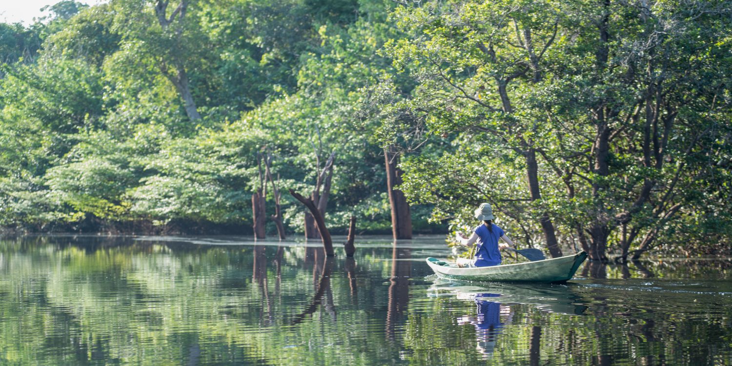 A woman takes a trip down the river in a traditional canoe.