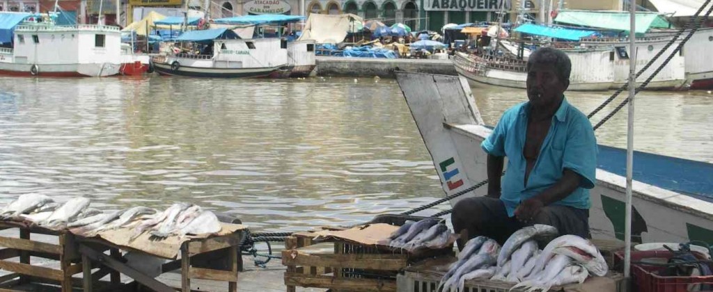 Man selling fish at the waters edge at Belém port. 
