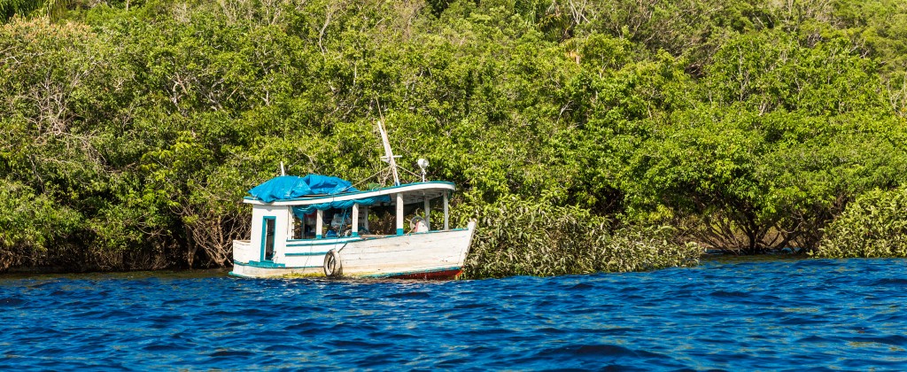 A boat docked on the banks of a choppy section of the Amazon river. 