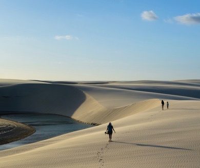 A group of people walking along "lencois maranheses."