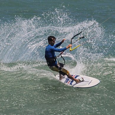 Panoramic shot of kitesurfer dropping in on a wave.