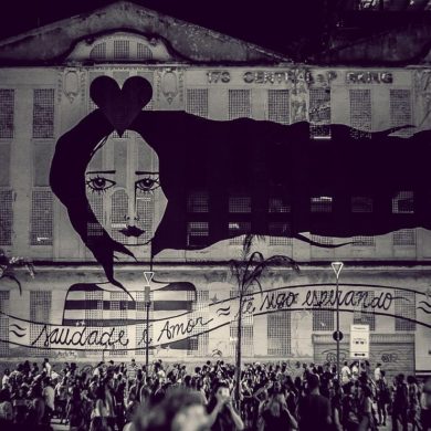 Black and white photo of crowd watching a projection on a wall in Brazil.